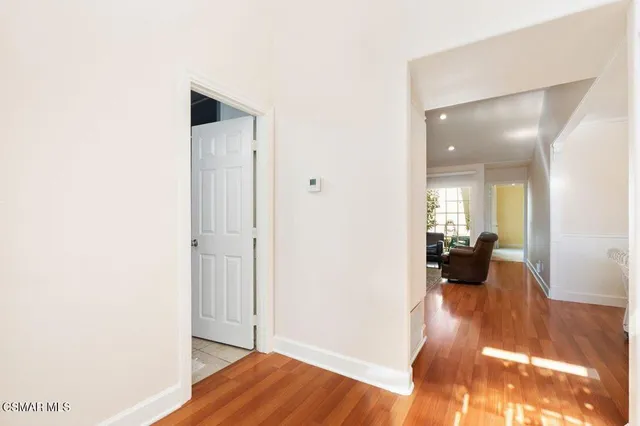 a view of a hallway with wooden floor and a living room