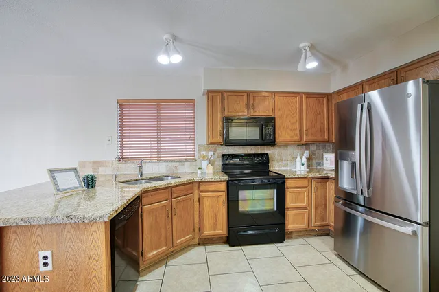 a kitchen with stainless steel appliances granite countertop a sink stove refrigerator and cabinets
