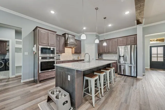 a kitchen with stainless steel appliances granite countertop a kitchen island hardwood floor sink stove and granite counter top