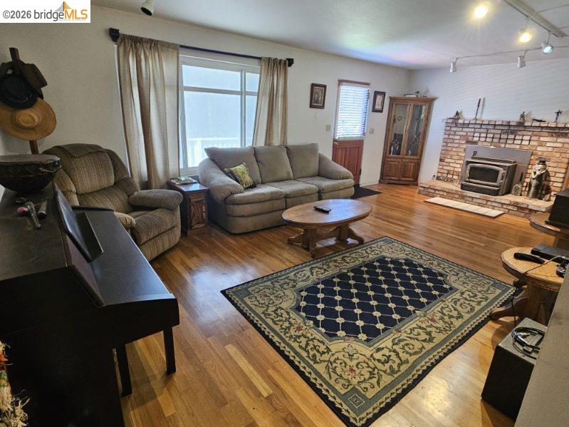 19967 Peaceful Oak Road Sonora, CA 95370 - Photo 5 of 35 Living room with hardwood / wood-style flooring, a wood stove, and track lighting