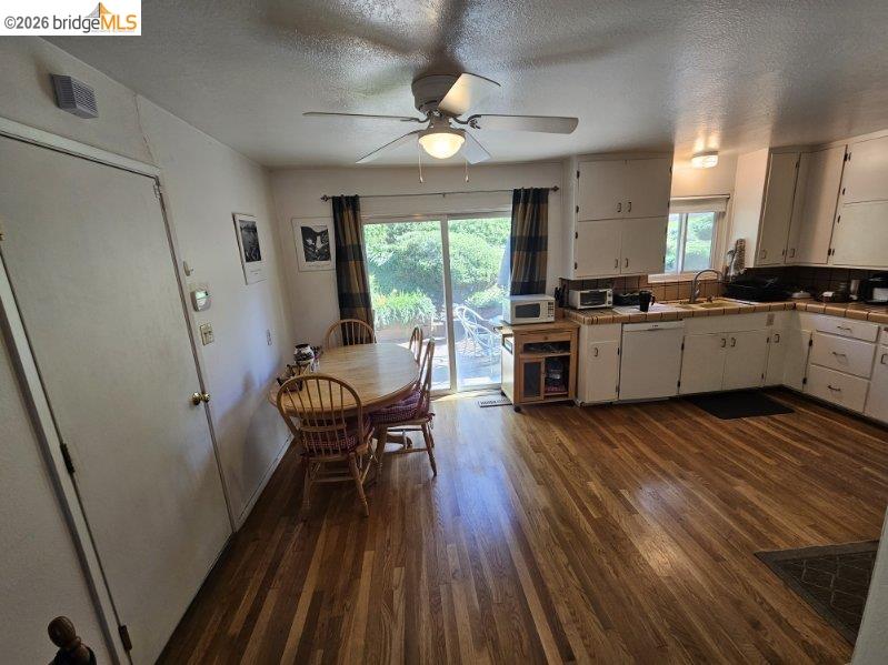 19967 Peaceful Oak Road Sonora, CA 95370 - Photo 6 of 35 Kitchen featuring tile countertops, dark wood-style flooring, a ceiling fan, a textured ceiling, and white cabinetry