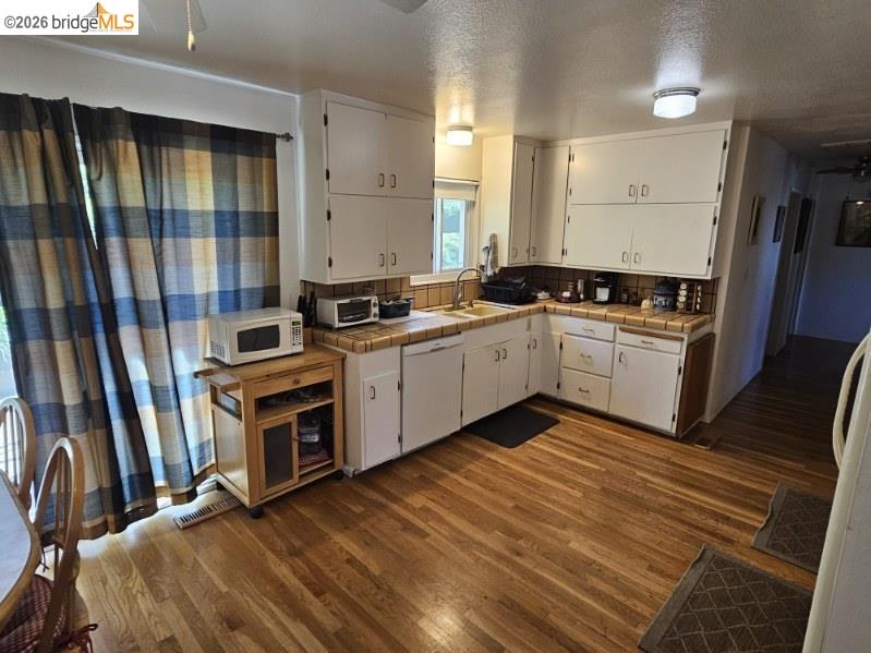 19967 Peaceful Oak Road Sonora, CA 95370 - Photo 7 of 35 Kitchen featuring tile countertops, white cabinets, dark wood finished floors, white appliances, and a textured ceiling