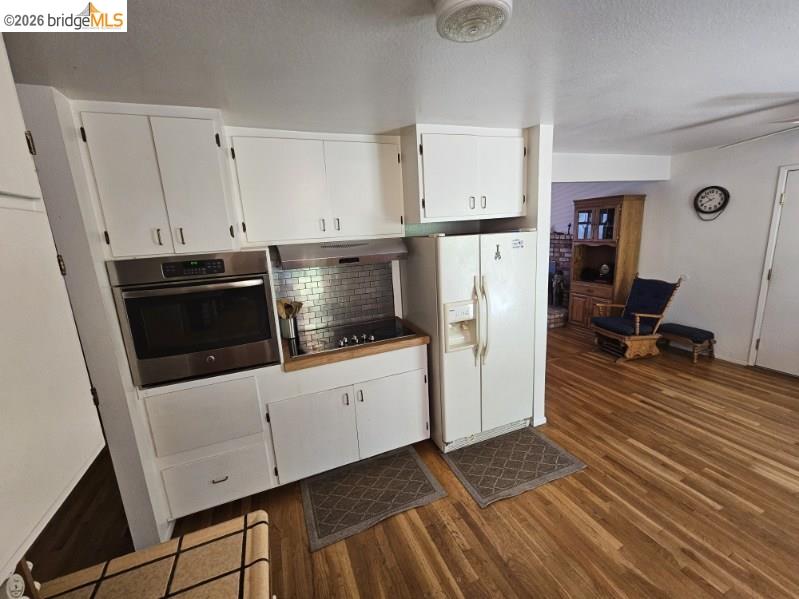 19967 Peaceful Oak Road Sonora, CA 95370 - Photo 9 of 35 Kitchen with white cabinetry, stainless steel oven, white fridge with ice dispenser, decorative backsplash, and dark wood-style flooring