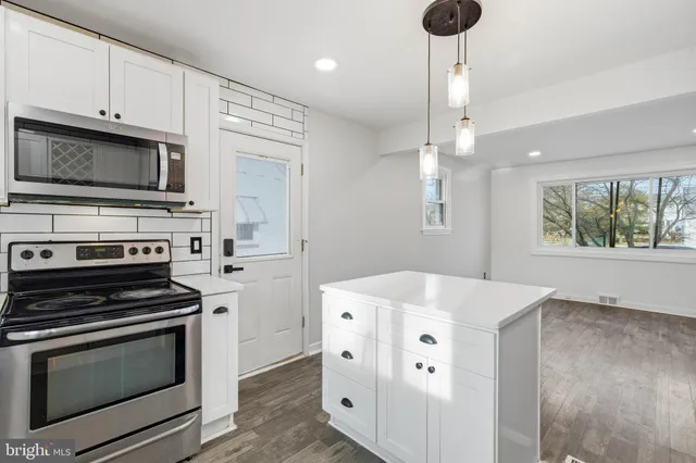 a kitchen with stainless steel appliances a stove a microwave and white cabinets