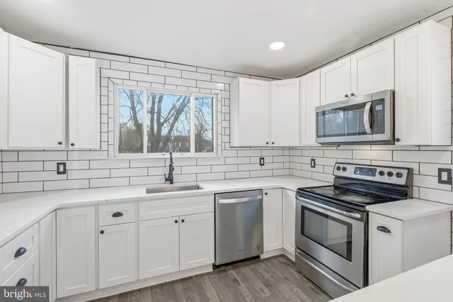 a kitchen with white cabinets appliances and a sink