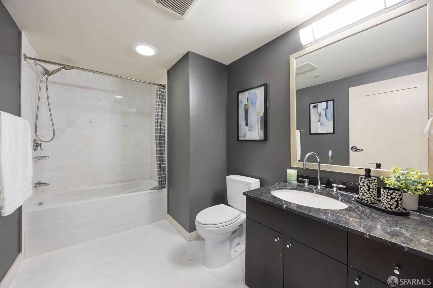 355 1st Street, Unit S2503 San Francisco, CA 94105 - Photo 32 of 67 a bathroom with a granite countertop sink toilet a large mirror a shower and a bathtub