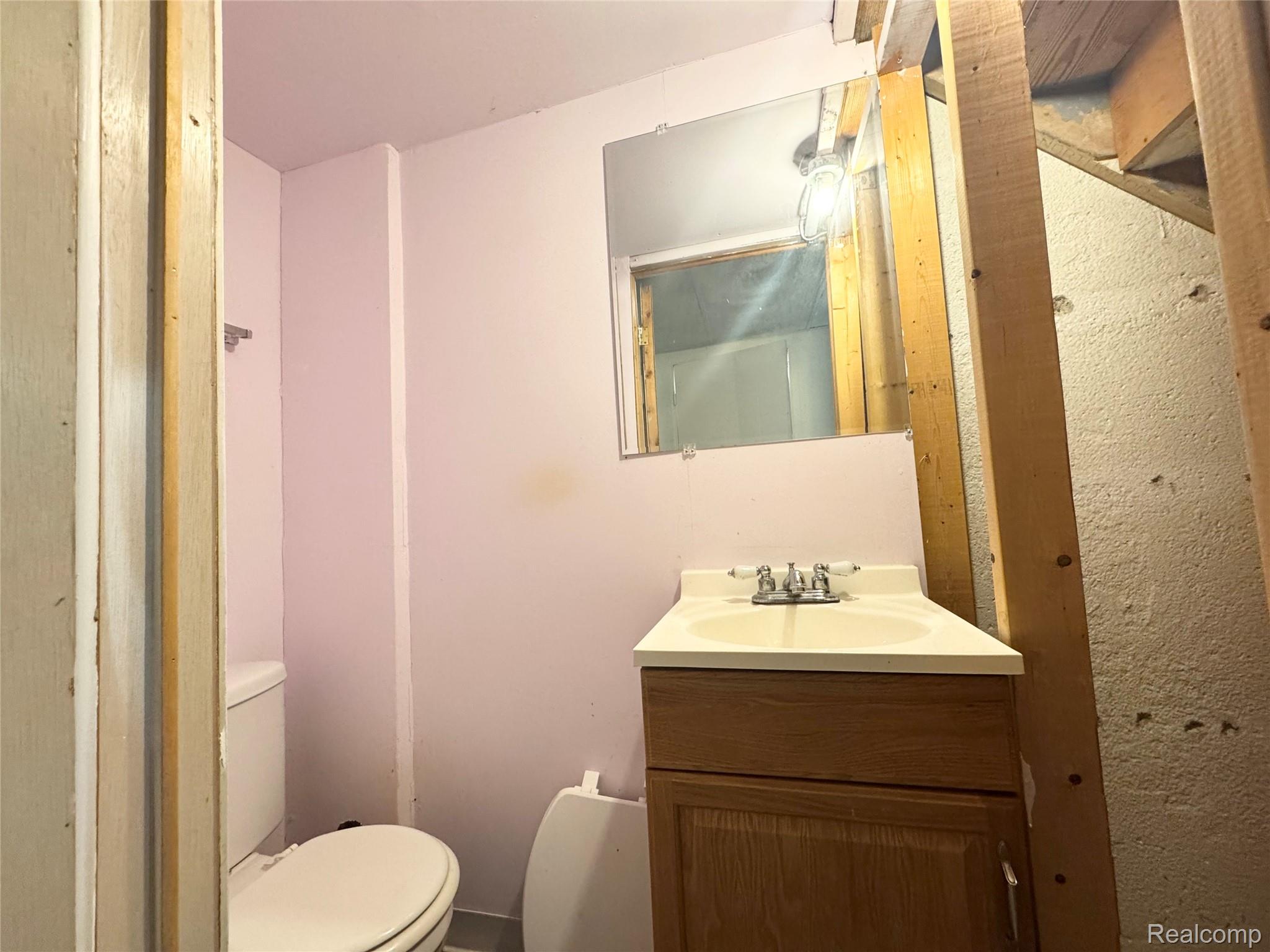 4386 15 Mile Road, Unit 64 Sterling Heights, MI 48310 - Photo 15 of 23 Compact bathroom featuring a single vanity with wood-finish cabinetry, a white countertop, and a chrome faucet