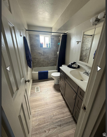 106 East Richelman Lane Wellington, UT 84542 - Photo 13 of 35 Full bathroom featuring vanity, a textured ceiling, shower / bathtub combination with curtain, and light wood-style floors