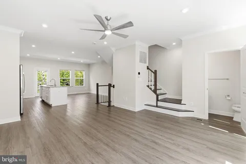 a view of an empty room with wooden floor and a ceiling fan