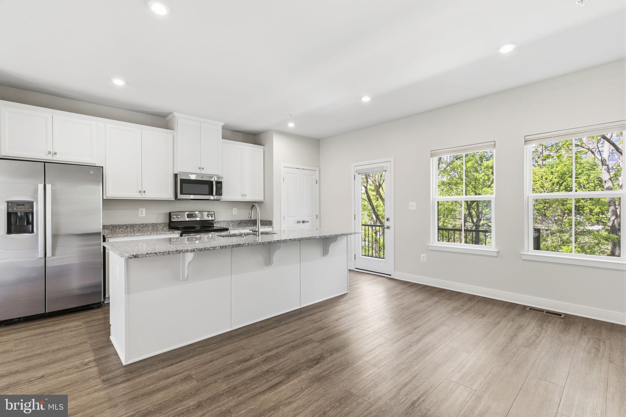 1566 Lowman Street Baltimore, MD 21230 - Photo 17 of 47 a large kitchen with stainless steel appliances granite countertop a stove a sink a refrigerator and white cabinets with wooden floor