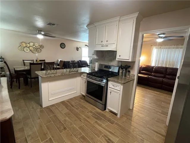 a kitchen with granite countertop a stove and white cabinets