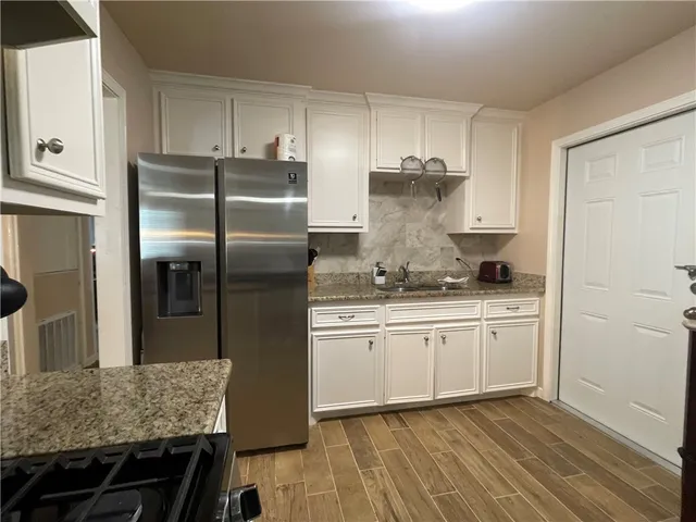 a kitchen with granite countertop stainless steel appliances a refrigerator and wooden cabinets