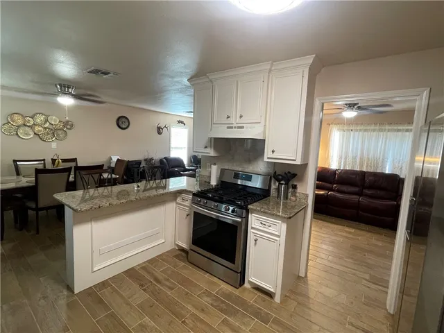 a kitchen with granite countertop a stove and white cabinets