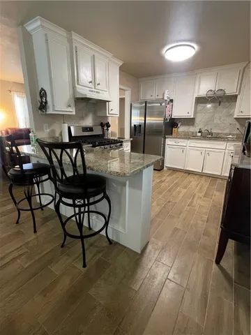 a kitchen with stainless steel appliances granite countertop a stove a sink a refrigerator and cabinets