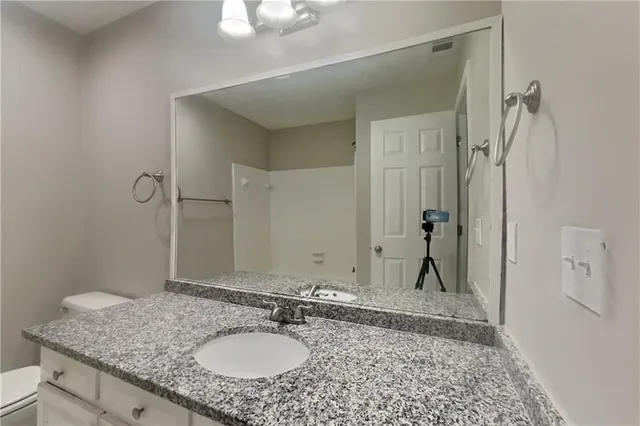 a bathroom with a granite countertop sink and a mirror