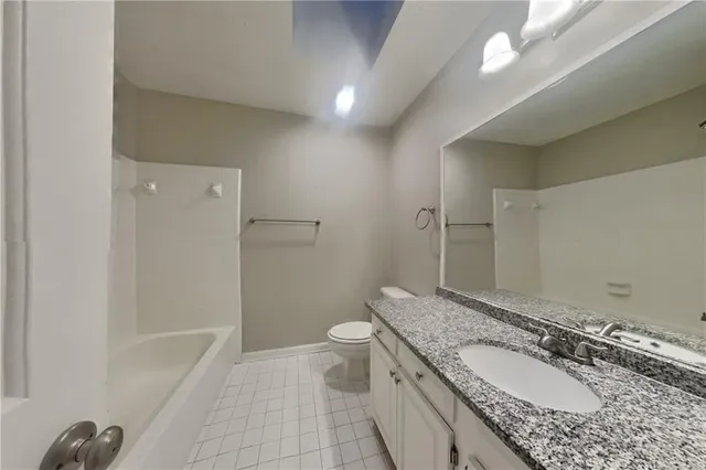 a bathroom with a granite countertop sink a toilet and shower