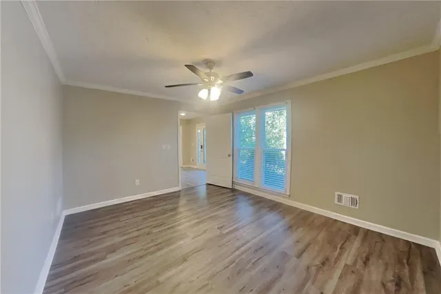 an empty room with wooden floor and a ceiling fan