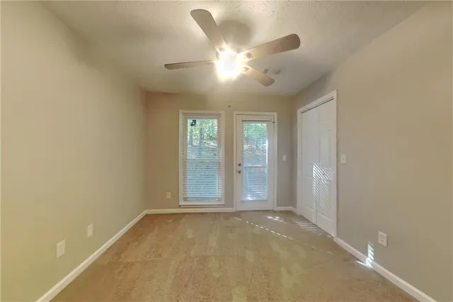 an empty room with windows and fan