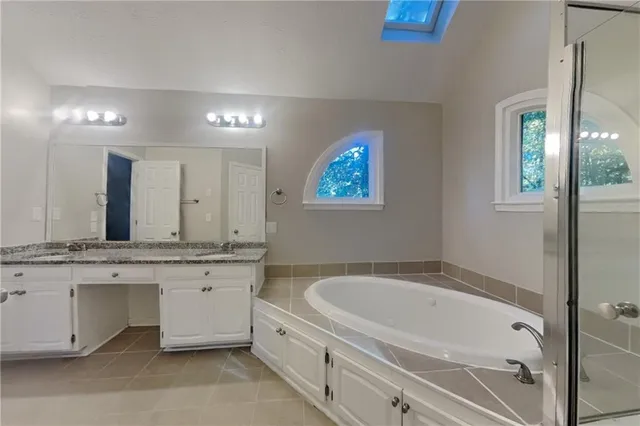 a bathroom with a tub a sink and mirror