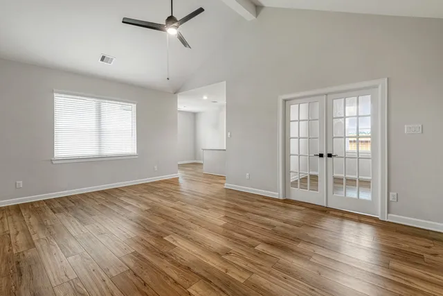 a view of an empty room with wooden floor and a window