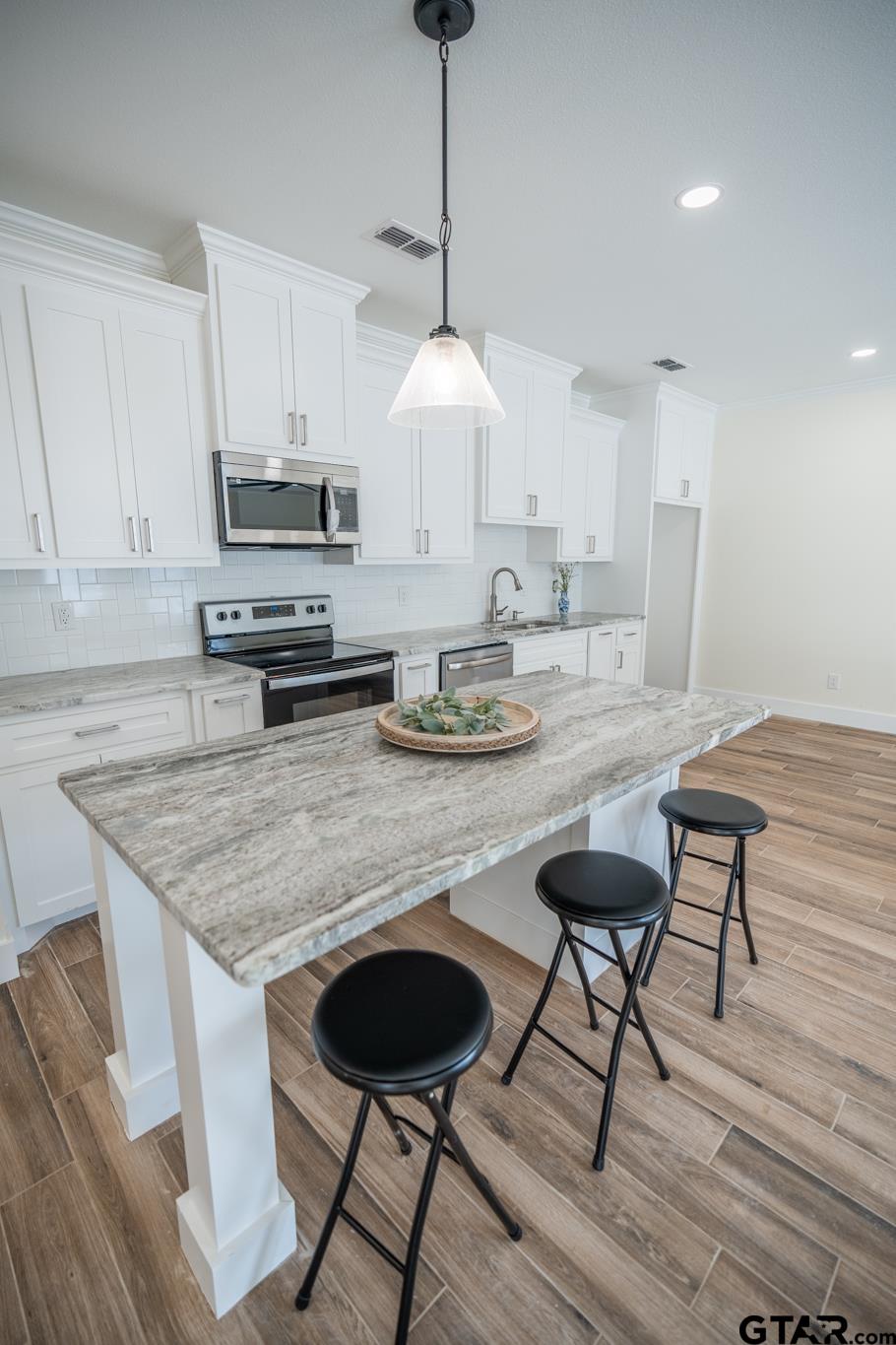 413 Stewart Street Lindale, TX 75771 - Photo 14 of 39 a kitchen with granite countertop a table chairs stove a sink dishwasher and cabinets with wooden floor