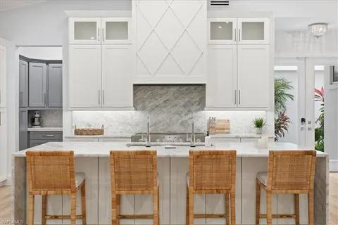 a kitchen with kitchen island granite countertop a stove a sink and white cabinets with wooden floor