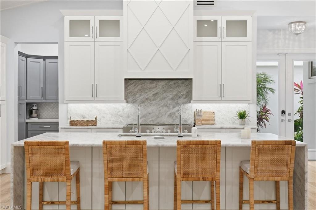 a kitchen with kitchen island granite countertop a stove a sink and white cabinets with wooden floor