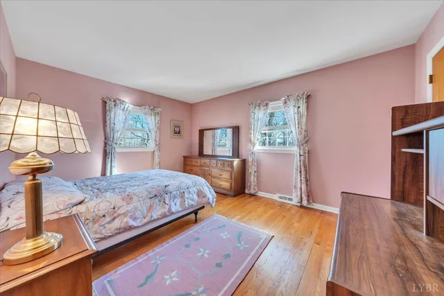 a bedroom with a bed and a dresser with wooden floor