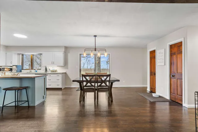 a dining room with wooden floor a chandelier a glass table and chairs