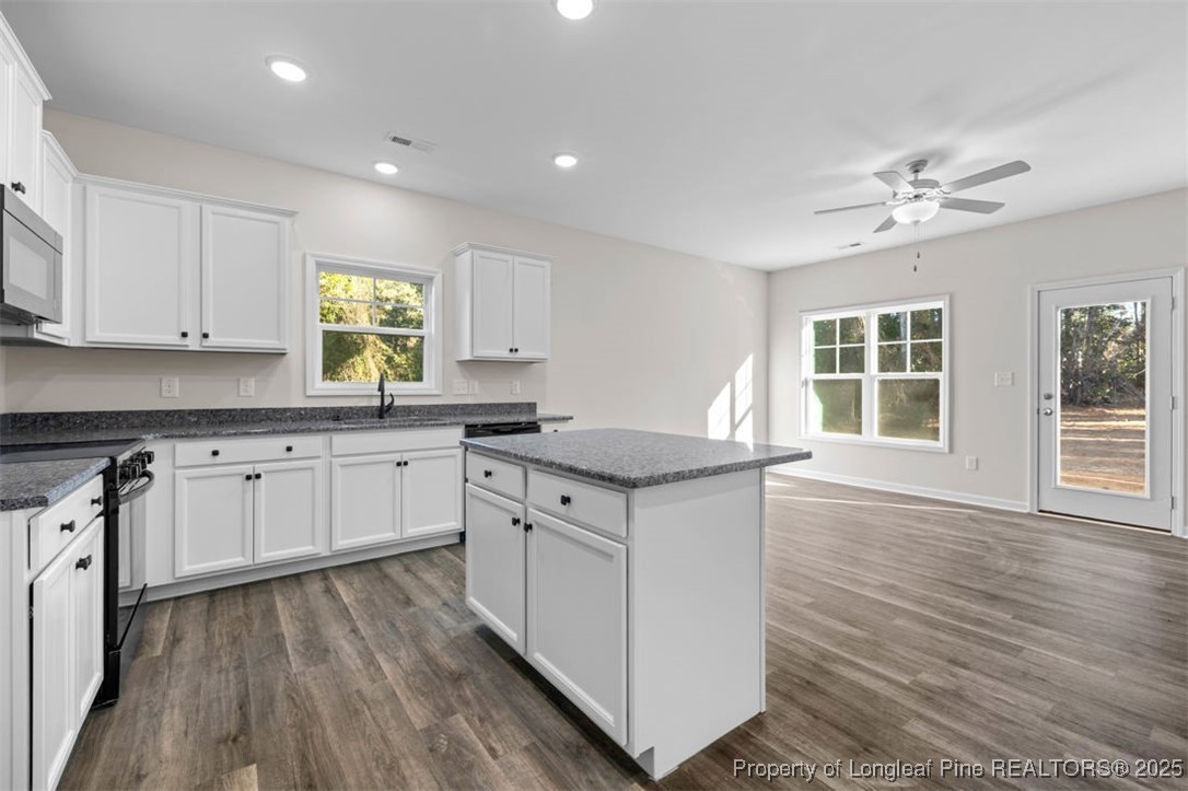 229 Ruritan Drive Fayetteville, NC 28314 - Photo 5 of 16 a kitchen with granite countertop a stove a sink dishwasher and white cabinets with wooden floor