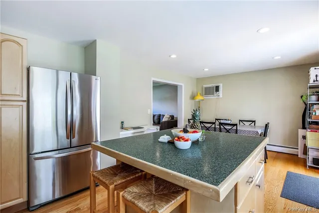 a kitchen with stainless steel appliances granite countertop a refrigerator a stove a dining table and chairs with wooden floor