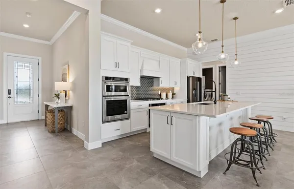 a kitchen with stainless steel appliances kitchen island granite countertop a dining table chairs and sink