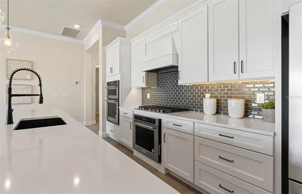 a kitchen with sink stove and white cabinets with wooden floor