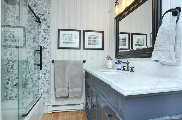 a bathroom with a granite countertop sink a mirror and shower