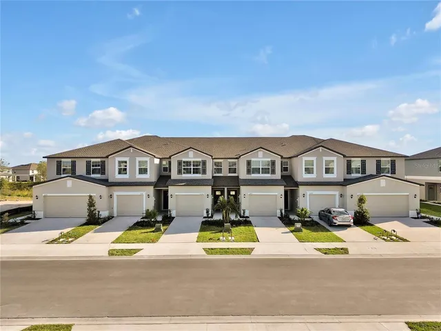 an aerial view of residential houses with yard and mountain view in back
