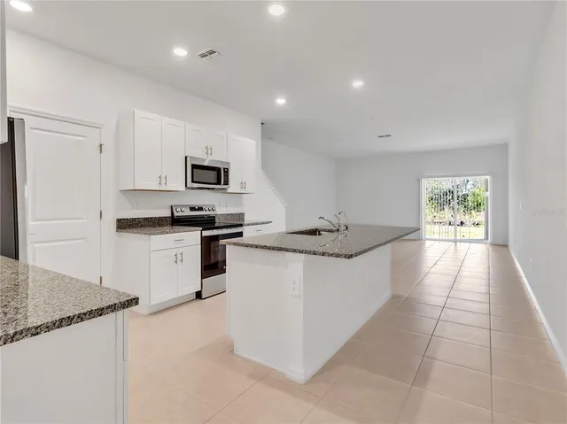 a kitchen with granite countertop a stove top oven and cabinets