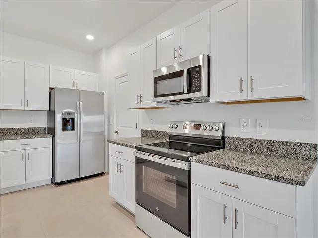a kitchen with white cabinets and stainless steel appliances