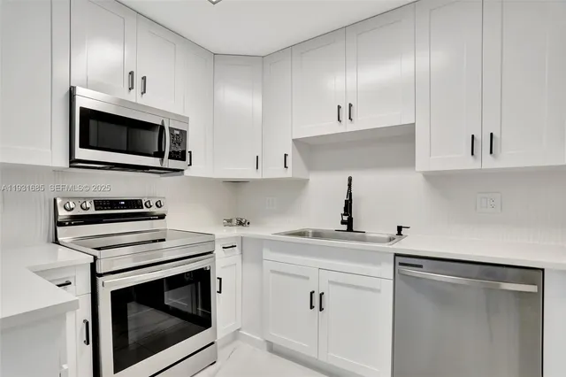 a kitchen with white cabinets stainless steel appliances and sink