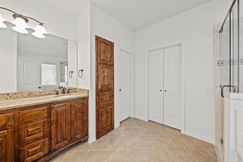 229 Firefly Drive Springtown, TX 76082 - Photo 13 of 33 Bathroom featuring a dual-sink vanity with a granite countertop, wood-finish cabinetry, and a large wall mirror