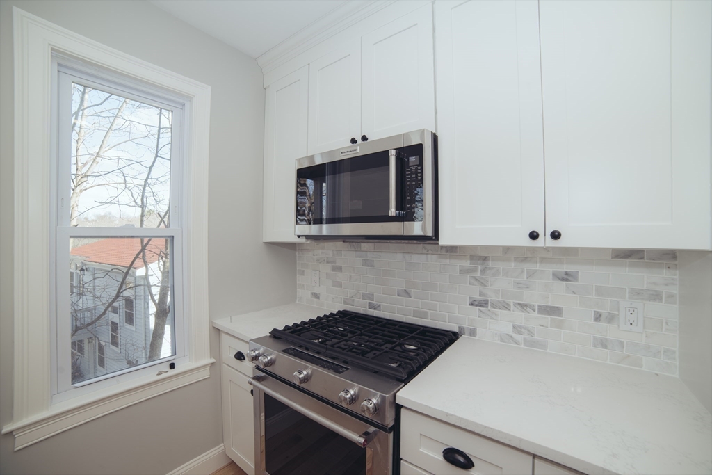 10 Duffley Court, Unit 1 Brookline, MA 02467 - Photo 3 of 23 a kitchen with granite countertop white cabinets stainless steel appliances and a window