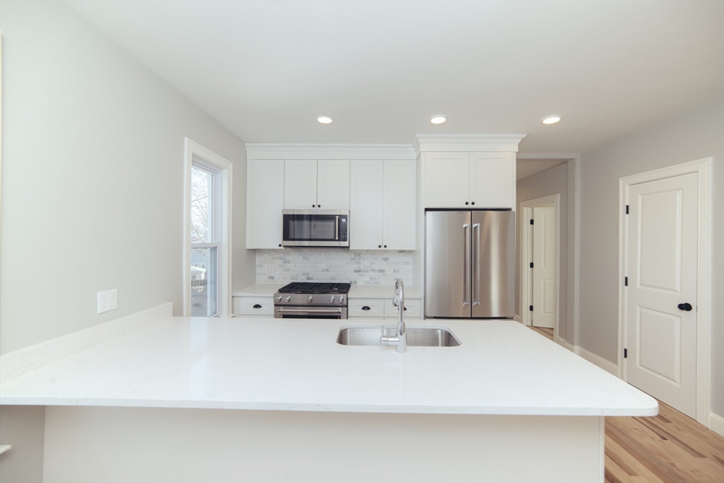 10 Duffley Court, Unit 1 Brookline, MA 02467 - Photo 5 of 23 a large white kitchen with stainless steel appliances a refrigerator a stove a sink and a stove