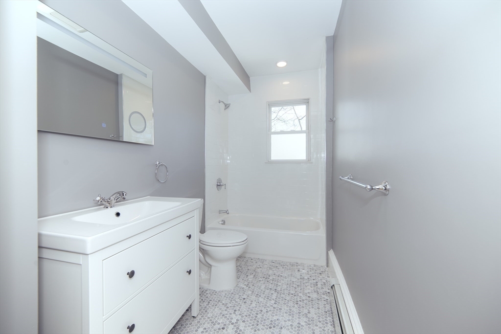 10 Duffley Court, Unit 1 Brookline, MA 02467 - Photo 9 of 23 a bathroom with a toilet a sink a mirror and vanity