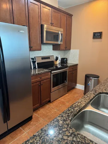 a kitchen with stainless steel appliances granite countertop a sink stove and refrigerator