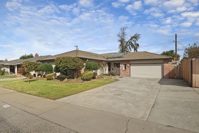 a view of house with a yard and potted plants