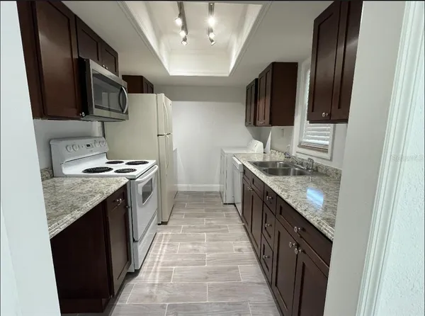a kitchen with stainless steel appliances granite countertop sink stove microwave and cabinets