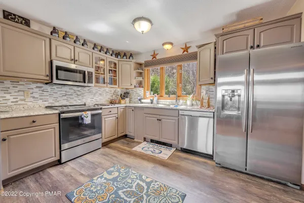 a living room with stainless steel appliances kitchen island granite countertop a stove a sink and a microwave