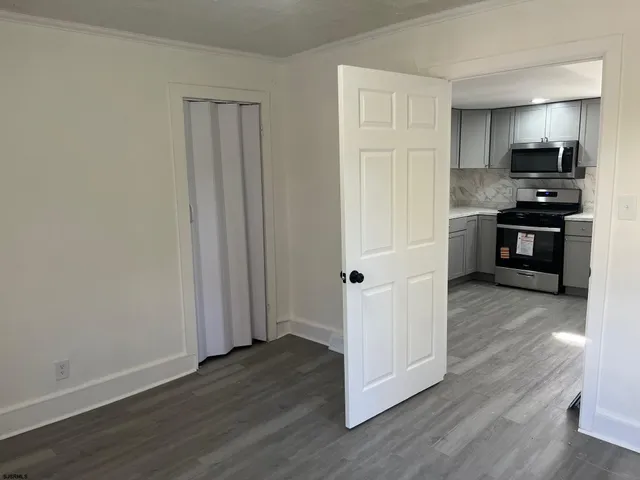 a view of kitchen with wooden floor electronic appliances and cabinets