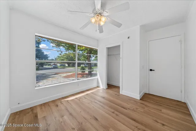 a view of empty room with wooden floor and fan