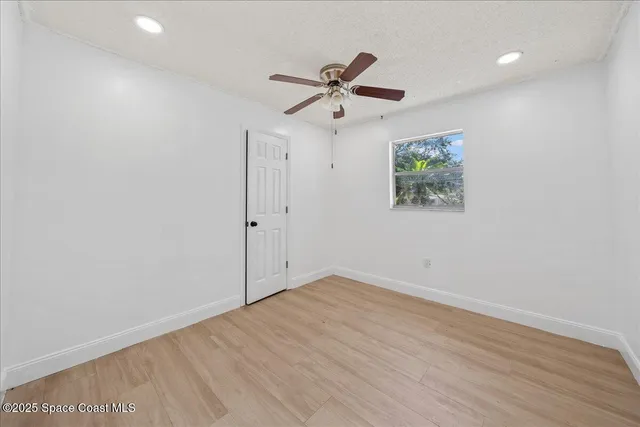 an empty room with wooden floor and ceiling fan