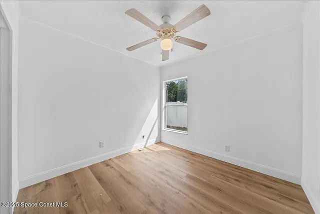 an empty room with a ceiling fan and window